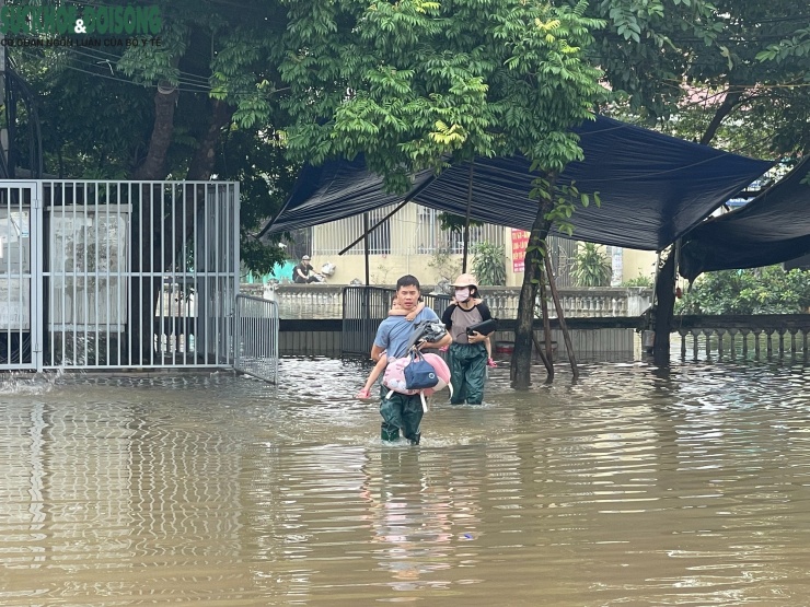 Người dân lội bì bõm cõng con qua dòng nước.