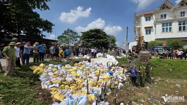 Dù trời nắng, hàng trăm người vẫn khẩn trương làm việc để khắc phục sự cố mạch sủi đê sông Cầu. 
