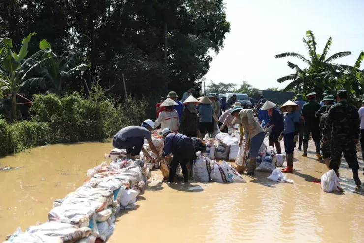 Lực lượng chức năng cùng nhân dân đắp bao đất, cát ngăn nước lũ tràn vào khu vực dân cư. Ảnh: CTV