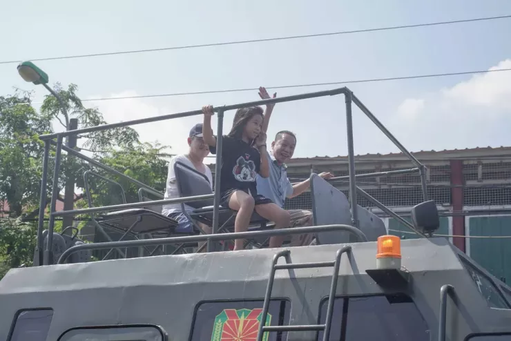 Người dân và một em nhỏ tỏ ra thích thú khi được ngồi xe đặc chủng lội qua khu vực bị ngập lụt trên tuyến Quốc lộ 3 cũ đoạn qua địa phận xã Trung Giã. Ảnh: Trọng Phú