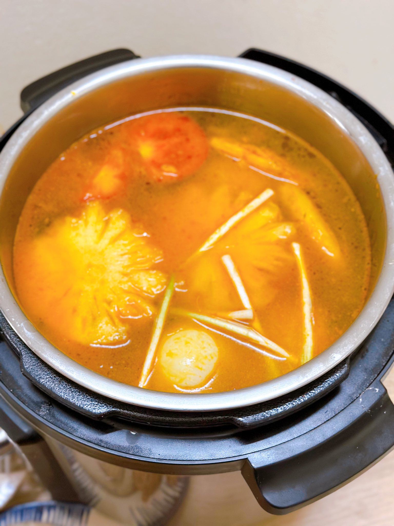Tiếp đến cho cà chua, dứa, bí đỏ, hành tây vào, thêm nước vừa ăn đun đến khi nước sôi, lúc này nêm nếm lại gia vị cho vừa ăn rồi tiếp tục đun tầm 5 phút nữa.