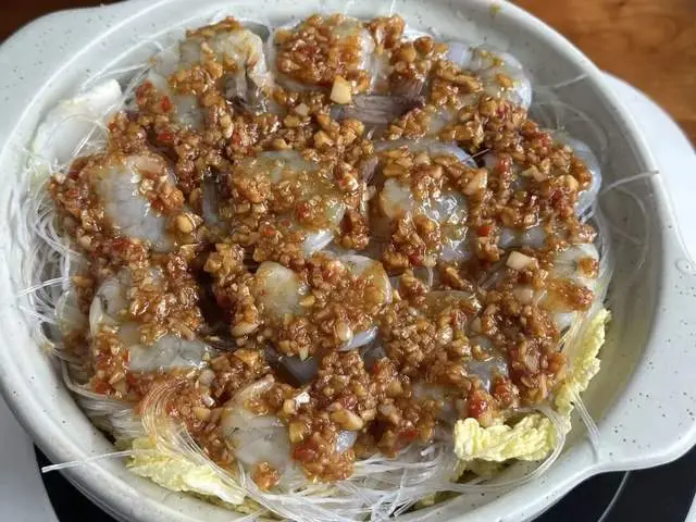 Cho thêm một lớp sốt tỏi lên tôm, rót vào một bát nước sôi (có thể cho nhiều hơn một chút vì miến hút nước khá nhanh). Đậy nắp và hầm khoảng 7–8 phút. Rắc thêm hành lá khi dọn ra.