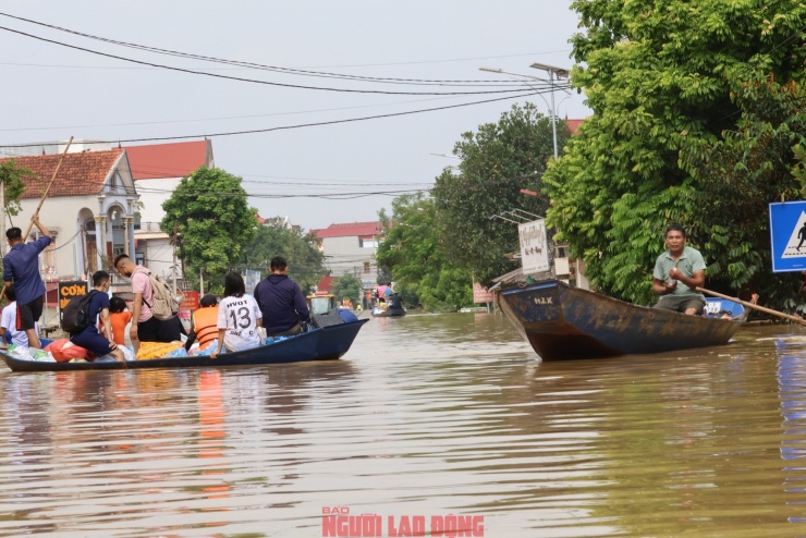 Nước ngập bao vây tứ phía, nhiều người dân phải sinh hoạt trên tầng hai và trên mái nhà. Nhu yếu phẩm được tiếp tế bằng thuyền, xuồng. Ảnh: Văn Duẩn