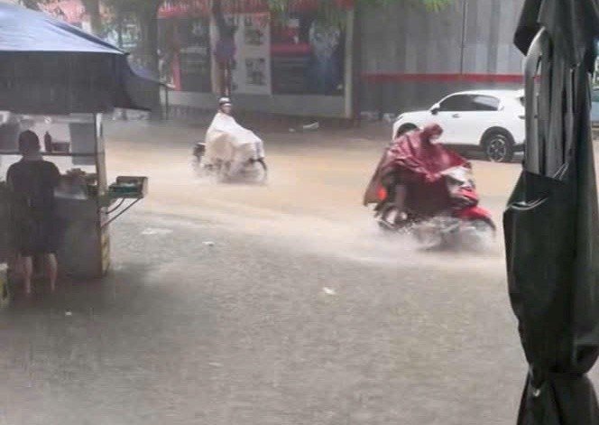 Nước ngập gần nửa bánh xe máy trên đường Nguyễn Tuân trong lúc mưa vẫn tiếp diễn.