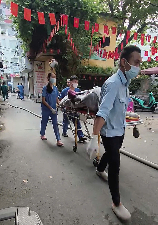 Thi thể được bọc kín bằng chăn đưa ra ngoài. Ảnh: Huy Mạnh