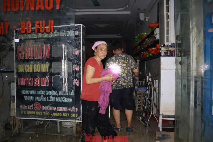 Một người dân đang thu dọn đống đổ nát trong nhà với gương mặt thẫn thờ. Toàn bộ cửa hàng cá hồi của gia đình đã bị trôi theo dòng nước lũ.