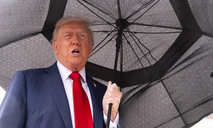 Tổng thống Mỹ che ô, bước lên chuyên cơ Không Lực Một ngày 12/10. Ảnh: AFP