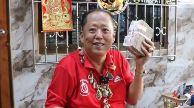 Ông Arnon cầm xấp tiền một triệu baht để treo thưởng cho người tát nhân tình của con trai. Ảnh: FB