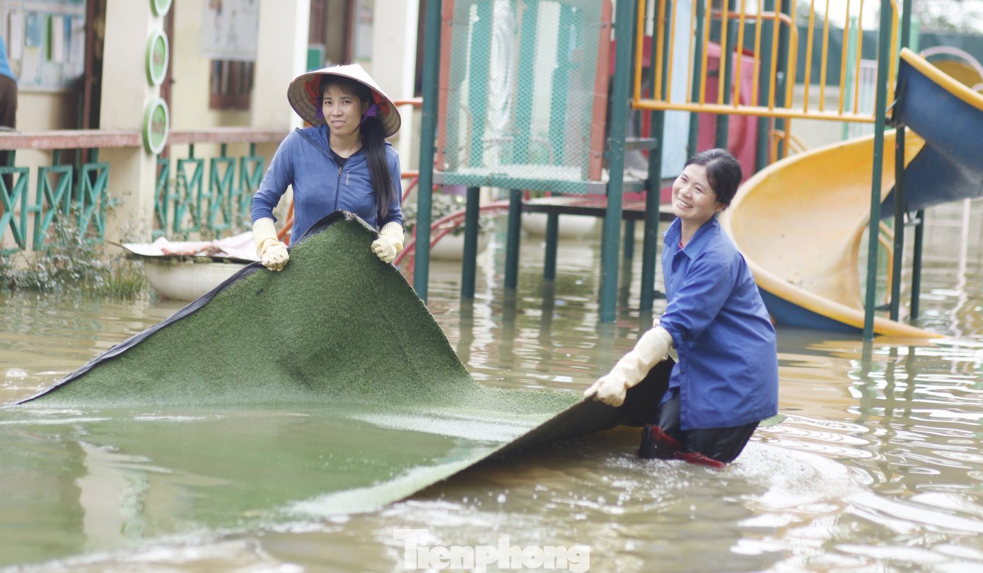 Các cô giáo và công an bì bõm lội nước thu dọn trường học. Ảnh: Nguyễn Thắng