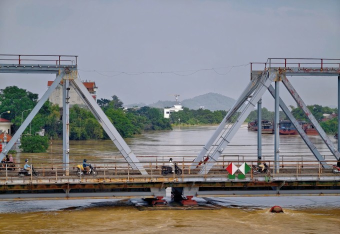 Cầu đường sắt Sông Thương dài 133 m, rộng 10,35 m, cao 9,5 m, gồm hai nhịp. Sau khi lũ rút, tàu chở xỉ quặng được di dời, người đi xe máy, xe thô sơ đã có thể di chuyển bình thường hai bên cầu. Ảnh: Kunmon