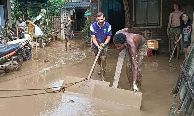 Du khách Colombia giúp gia đình ở phường Hà Giang, tỉnh Tuyên Quang dọn bùn sau lũ hồi đầu tháng 10. Ảnh: NVCC