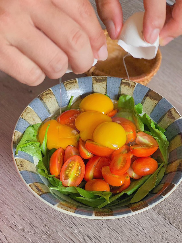 Sau đó có thể cắt nhỏ cải bó xôi hoặc không cắt nhỏ thì chọn lá nhỏ hoặc mua cải bó xôi baby ở các siêu thị. Cà chua bi bổ dọc làm đôi. Lần lượt cho vào bát to đập trứng gà vào. Cho nước mắm đánh đều nguyên liệu.