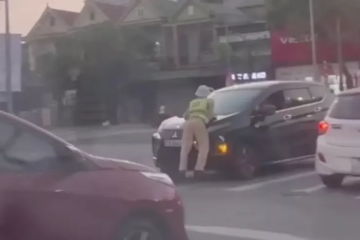 Tài xế không chấp hành hiệu lệnh, CSGT bị hất lên nắp capo. Ảnh cắt từ video clip.