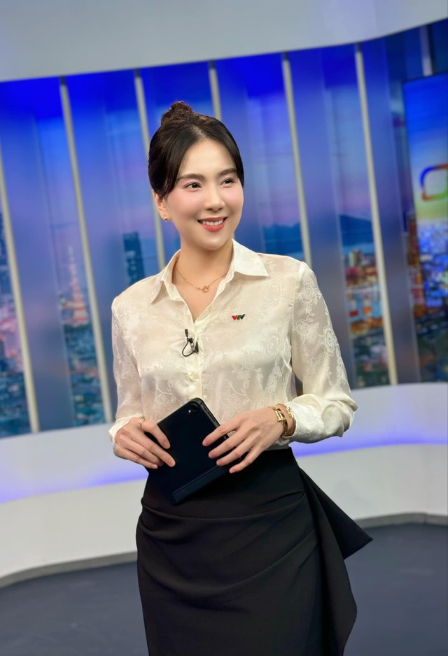 Ngoài vest, BTV Mai Ngọc mix đồ công sở với áo sơ mi điệu đà cùng chân váy tối màu nền nã.