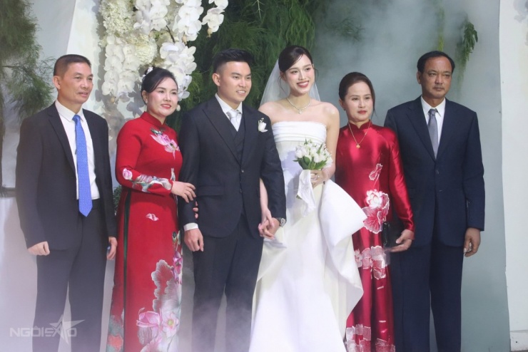 Vợ chồng Đỗ Thị Hà chụp hình cùng bố mẹ hai bên. Sau khi tiễn con gái cùng đoàn rước dâu, mẹ ruột hoa hậu - bà Hoa - đi một xe khác, kịp có mặt ở hôn lễ của con gái.