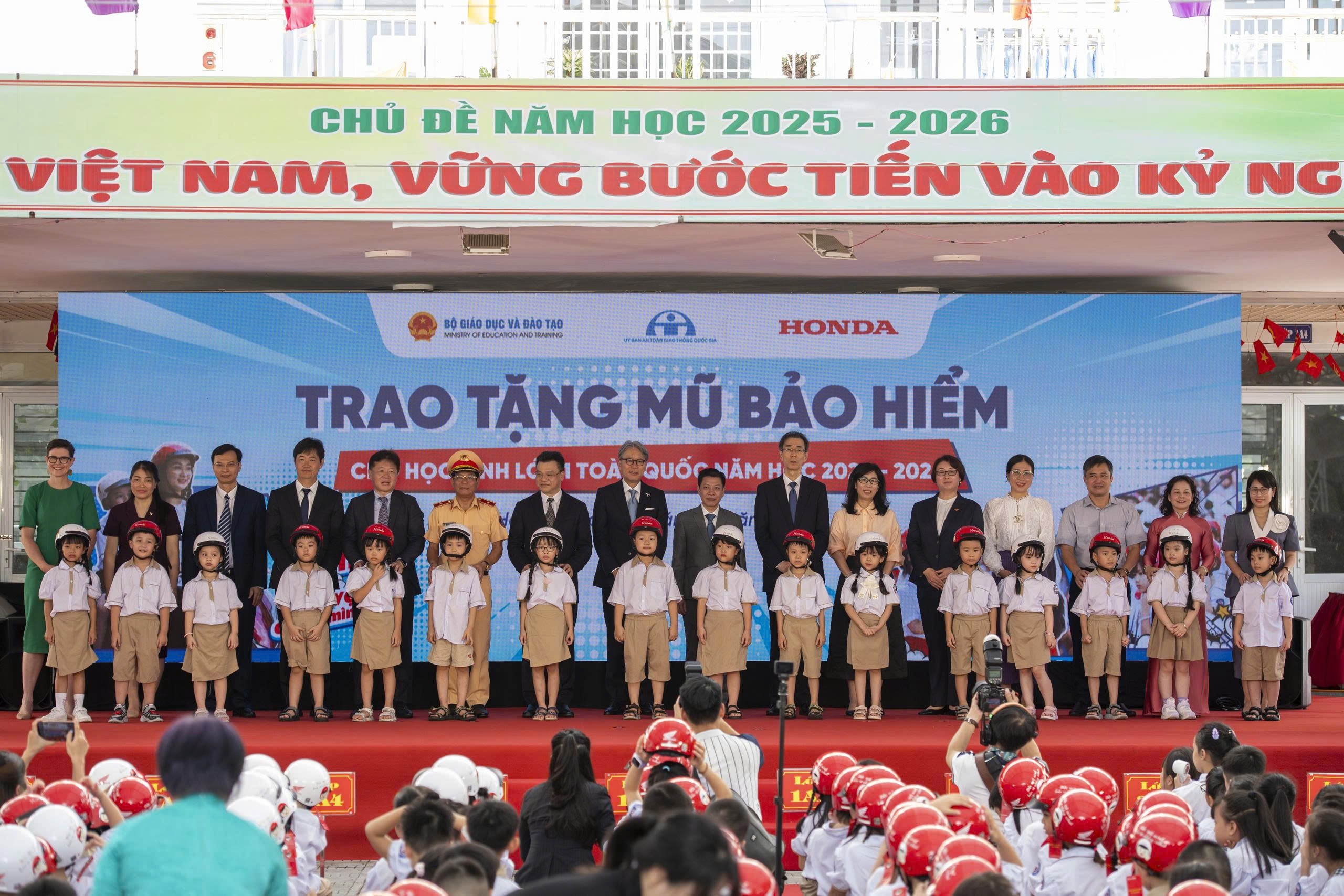 Các đại biểu trao tặng mũ bảo hiểm cho các em học sinh lớp Một trường Tiểu học Vạn Bảo