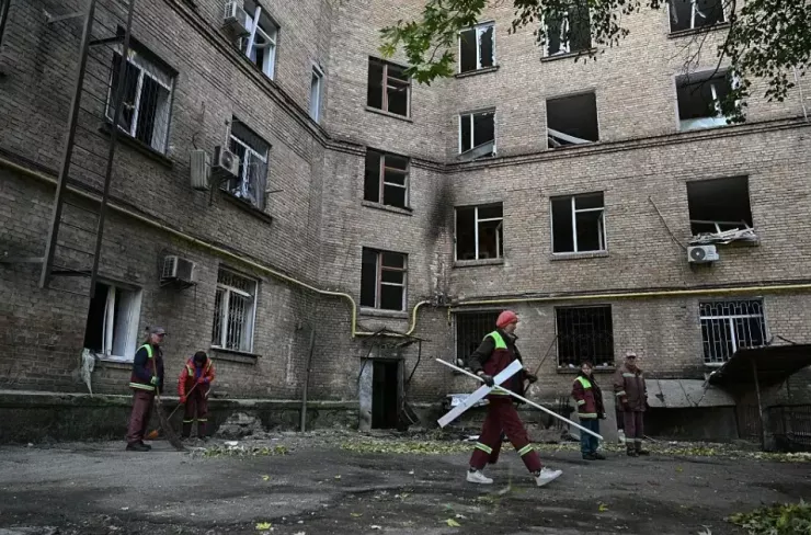 Công nhân ở Kiev ngày 22-10 dọn dẹp đống đổ nát trong sân của một khu chung cư bị hư hại do Nga tấn công tên lửa và UAV. Ảnh: AFP