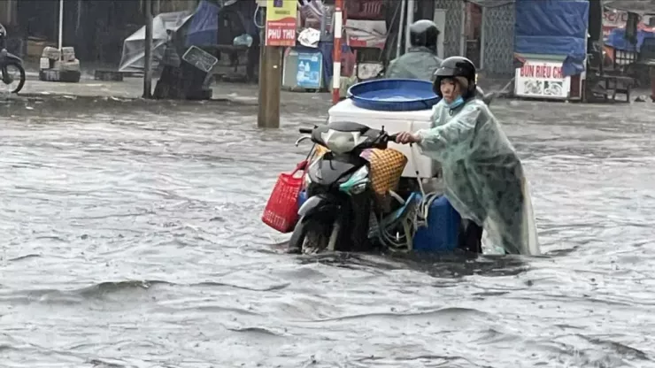 Đường ngập sâu, người dân phải dắt xe lội nước. Ảnh: M.N