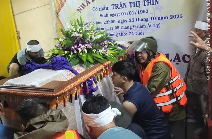 Công an phường Phú Xuân giúp một gia quyến ở đường Trần Quốc Toản đưa quan tài người quá cố lên cao, tránh ngập lụt. Ảnh: Công an cung cấp.