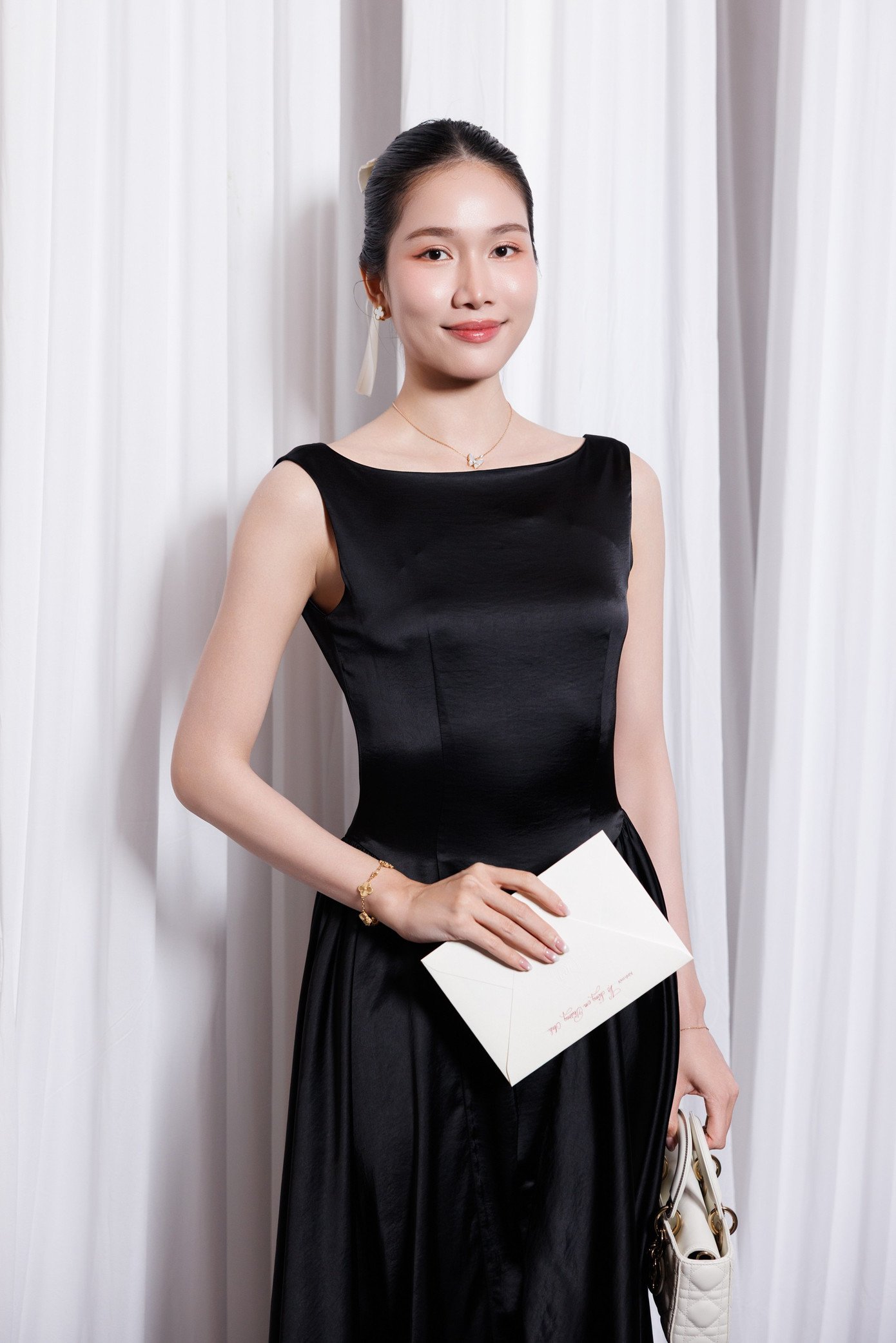Á hậu Phương Anh chọn váy đen cổ thuyền tối giản, kết hợp trang sức ngọc trai. Bên cạnh, Á hậu Tuyết Như diện váy trắng dáng bất đối xứng, khoe vai trần khỏe khoắn. Cả hai đồng loạt chọn lối trang điểm nhẹ, tinh tế.