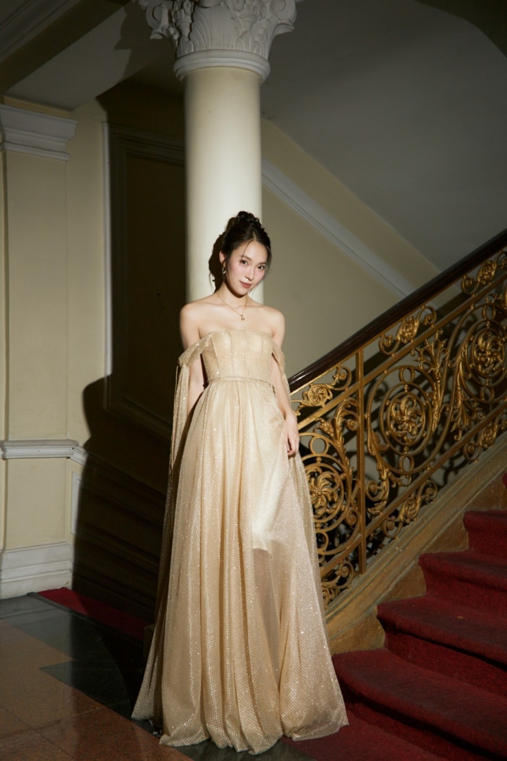 Để phù hợp với không gian của một khán phòng tại TP HCM, cô chọn đầm lưới tông màu ánh kim. Thân váy dựng phom corset giúp người đẹp thon gọn hơn.