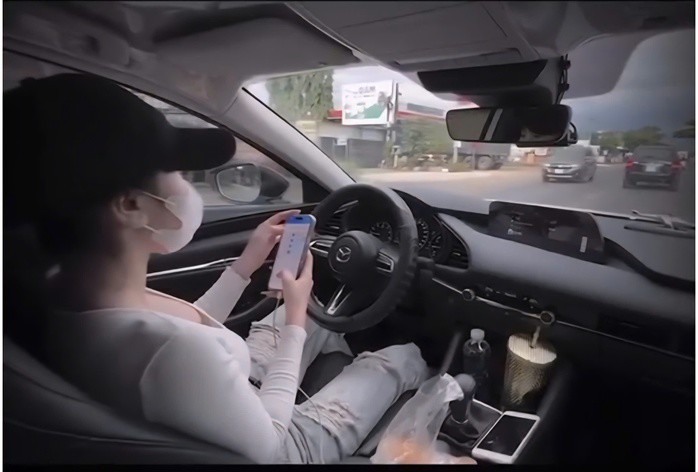 Hình ảnh cô gái buông 2 tay khỏi vô-lăng, lướt điện thoại khi điều khiển ô tô. Ảnh cắt từ clip