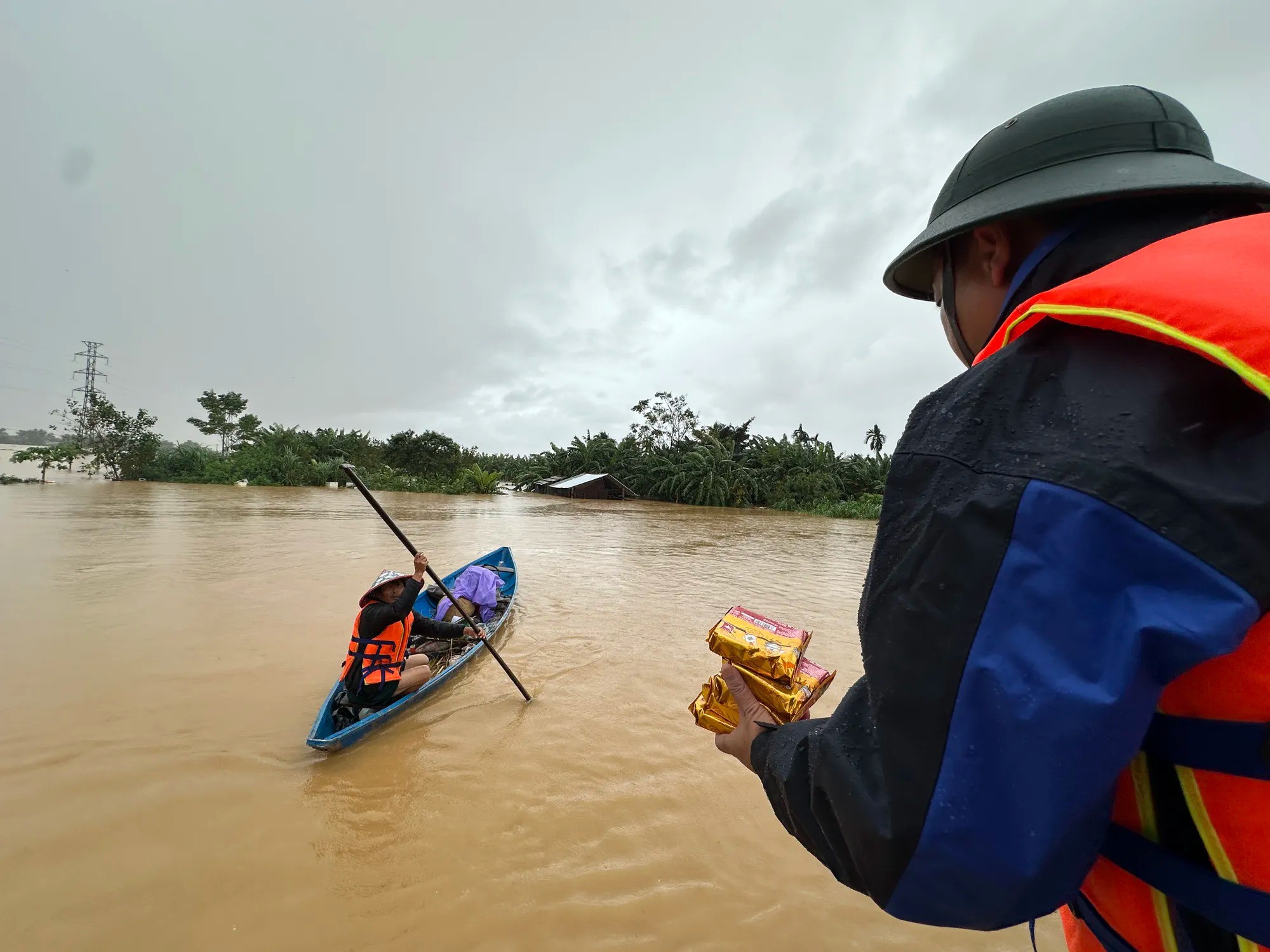 Ông Nguyễn Hảo (mặc áo phao) tiếp tế thức ăn cho người dân vùng rốn lũ. Ảnh: THANH NHẬT