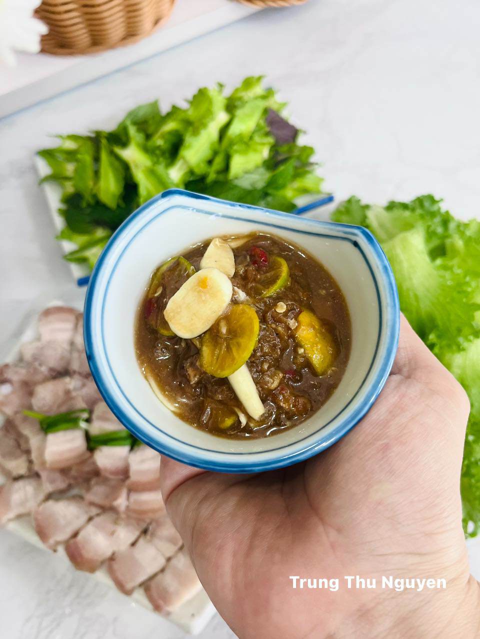 Cách làm mắm nêm chấm thịt: Giã nhuyễn tỏi ớt, cho mắm nêm vào, thêm đường, tỏi và quất thái lát vào là xong.