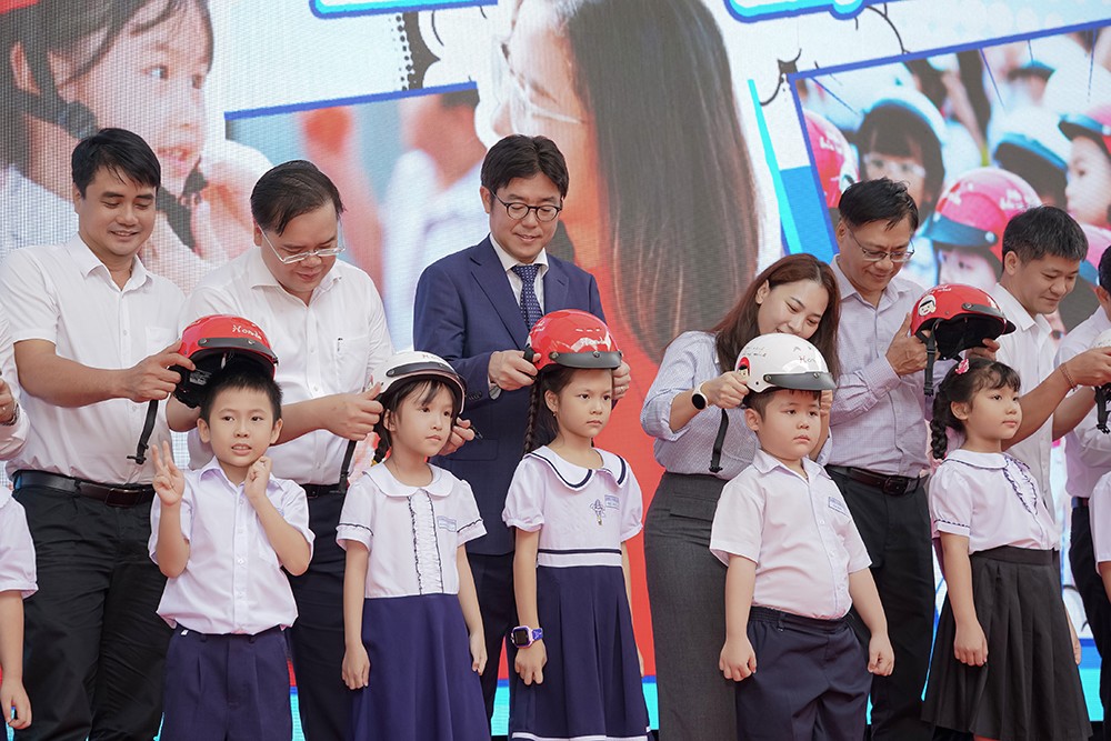 Các đại biểu trao tặng mũ bảo hiểm cho các em học sinh lớp Một trường Tiểu học Hoàng Dư Khương