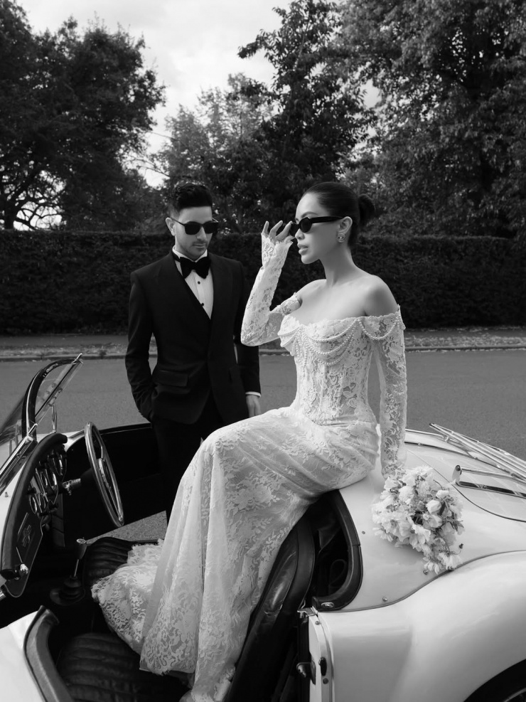 Tiên Nguyễn chọn đầm cưới phong cách gợi cảm của thương hiệu Berta khi thực hiện loạt ảnh trên đường phố. Chất liệu ren, đính kết ngọc trai theo phong cách retro là điểm nhấn của trang phục. Đây cũng là xu hướng được nhiều hãng lăng xê trong mùa mốt năm nay. Để tăng điểm nhấn, Tiên Nguyễn kết hợp kính râm, khuyên tai metallic của Chanel.