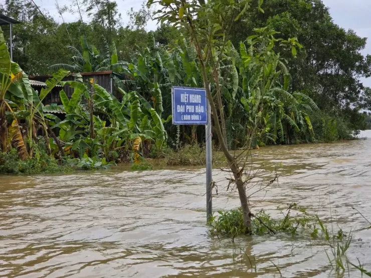 Nước lũ cao gần ngập bảng chỉ dẫn đường. Ảnh: MINH TRƯỜNG