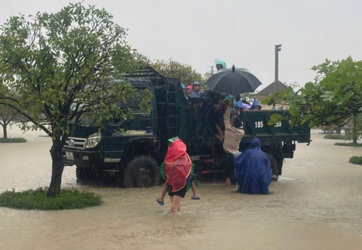Nước ngập sâu trên nhiều tuyến đường, một số phụ huynh đã sử dụng xe tải đến trường đón các cháu nhỏ. Trong ảnh, tại sân trường Tiểu học Kỳ Thịnh 1, phụ huynh xắn quần, lội nước để đón học sinh lên xe để đưa về nhà.