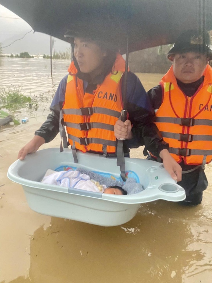 Công an phường Vũng Áng hỗ trợ đưa trẻ sơ sinh cùng gia đình ra khỏi khu vực ngập sâu. Ảnh: CTV