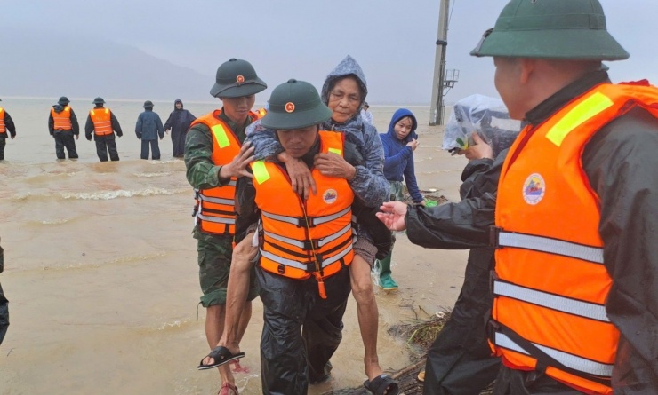 Lực lượng chức năng cõng dân qua khu vực bị ngập sâu. Ảnh: CTV