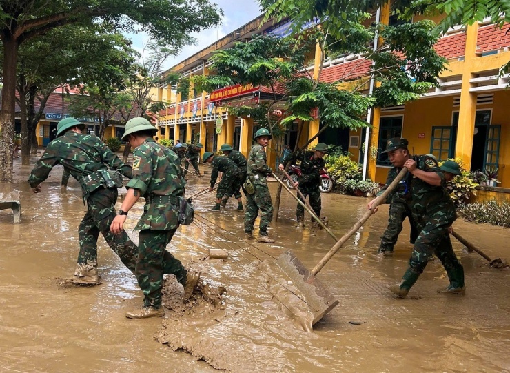 Các chiến sĩ dọn dẹp bùn, làm sạch sân trường để học sinh sớm quay lại lớp. Ảnh: G.X