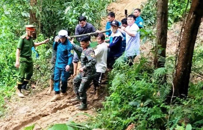 Lực lượng chức năng phối hợp với các y, bác sĩ khiêng sản phụ D. theo đường rừng, vượt qua cung đường bị sạt lở.