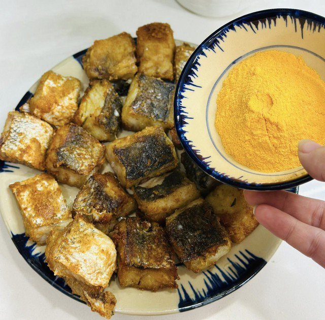 Khi cá còn nóng, rắc phô mai bột lên, lắc nhẹ cho phô mai bám đều. Ảnh: Thanh Huệ