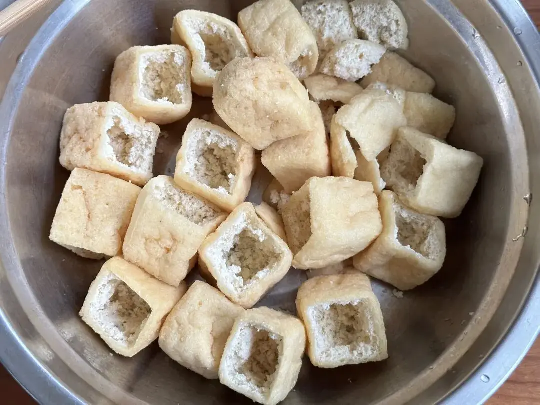 Dùng kéo cắt một mặt của đậu phụ chiên, dùng đũa nhẹ nhàng làm rỗng phần ruột bên trong.