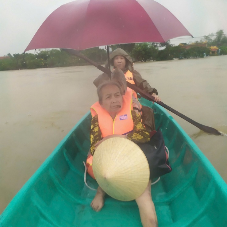 Lực lượng công an chèo thuyền đưa người dân qua vùng lũ để đến nơi an toàn.