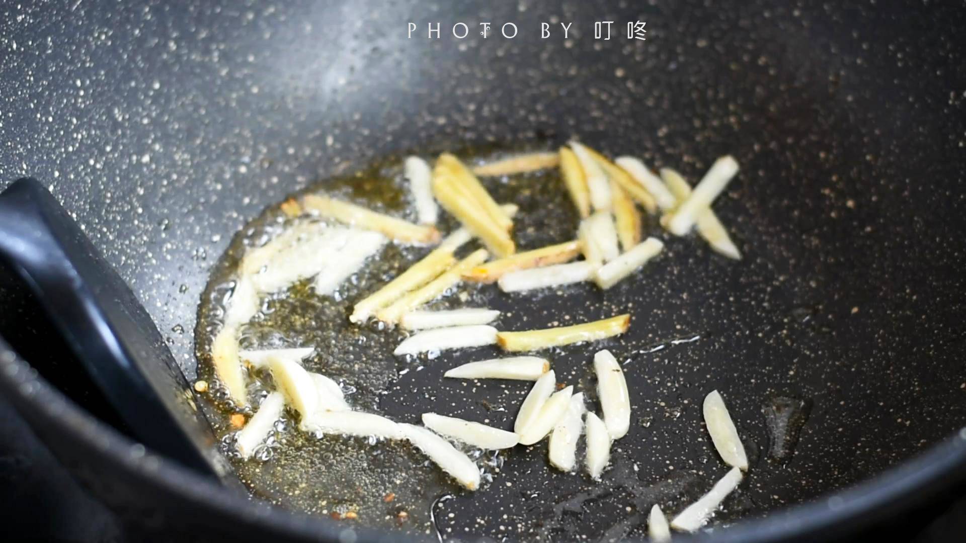 Tiếp tục cho 1 thìa dầu ăn vào chảo, đun nóng rồi cho gừng và tỏi vào phi thơm.