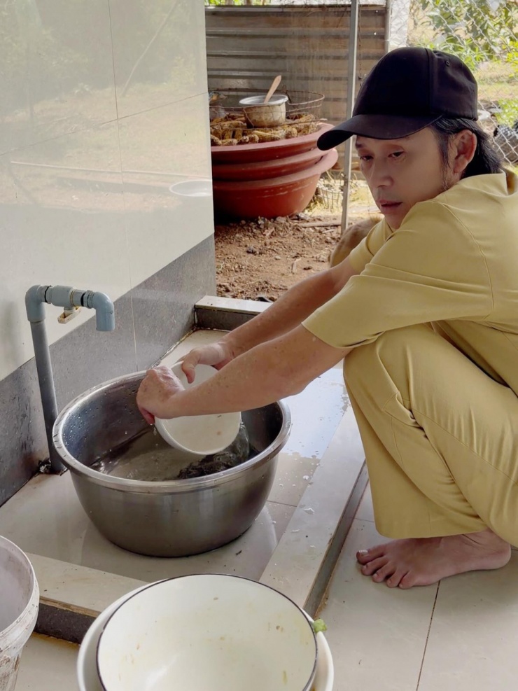 Nghệ sĩ Hoài Linh mặc trang phục giản dị, ngồi rửa bát sau nhà.