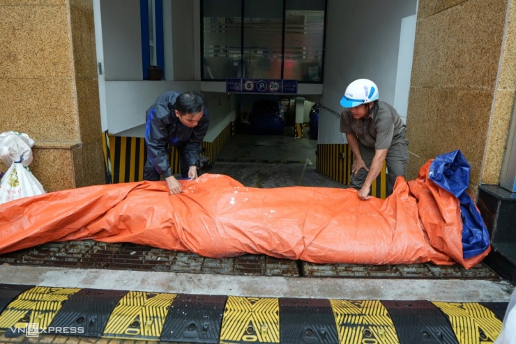 Trước cửa tòa nhà ngân hàng trên đường Nguyễn Thái Học (phường Quy Nhơn Nam), ông Nguyễn Mạnh Hùng, quản lý tòa nhà cùng nhóm nhân viên tất bật dựng kè tạm bằng bao nylon để ngăn nước tràn vào hầm xe.