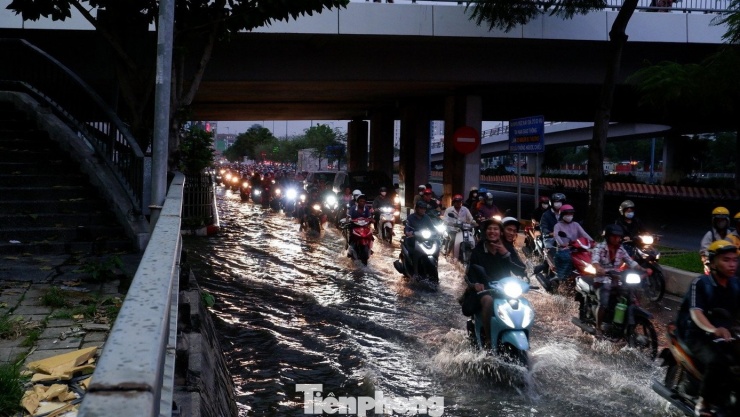 Người dân TPHCM di chuyển trong triều cường. Ảnh: Hữu Huy