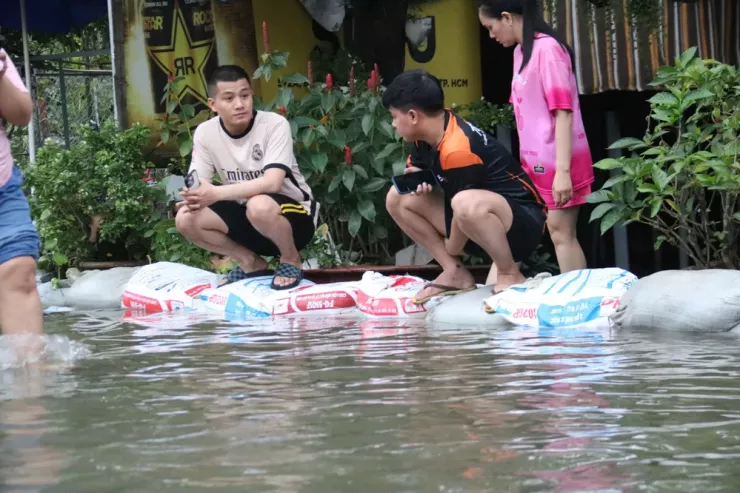 Người dân túc trực ngồi canh dòng nước dâng cao.