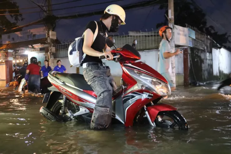 Chị Lan Hương (phường Bình Quới) chật vật dắt chiếc xe chết máy qua đoạn ngập sâu. “Tháng này ngập hoài, nước ngập hơn nửa bánh xe khiến tôi không thể chạy được, bất lực lắm" - chị nói, giọng đầy mệt mỏi.