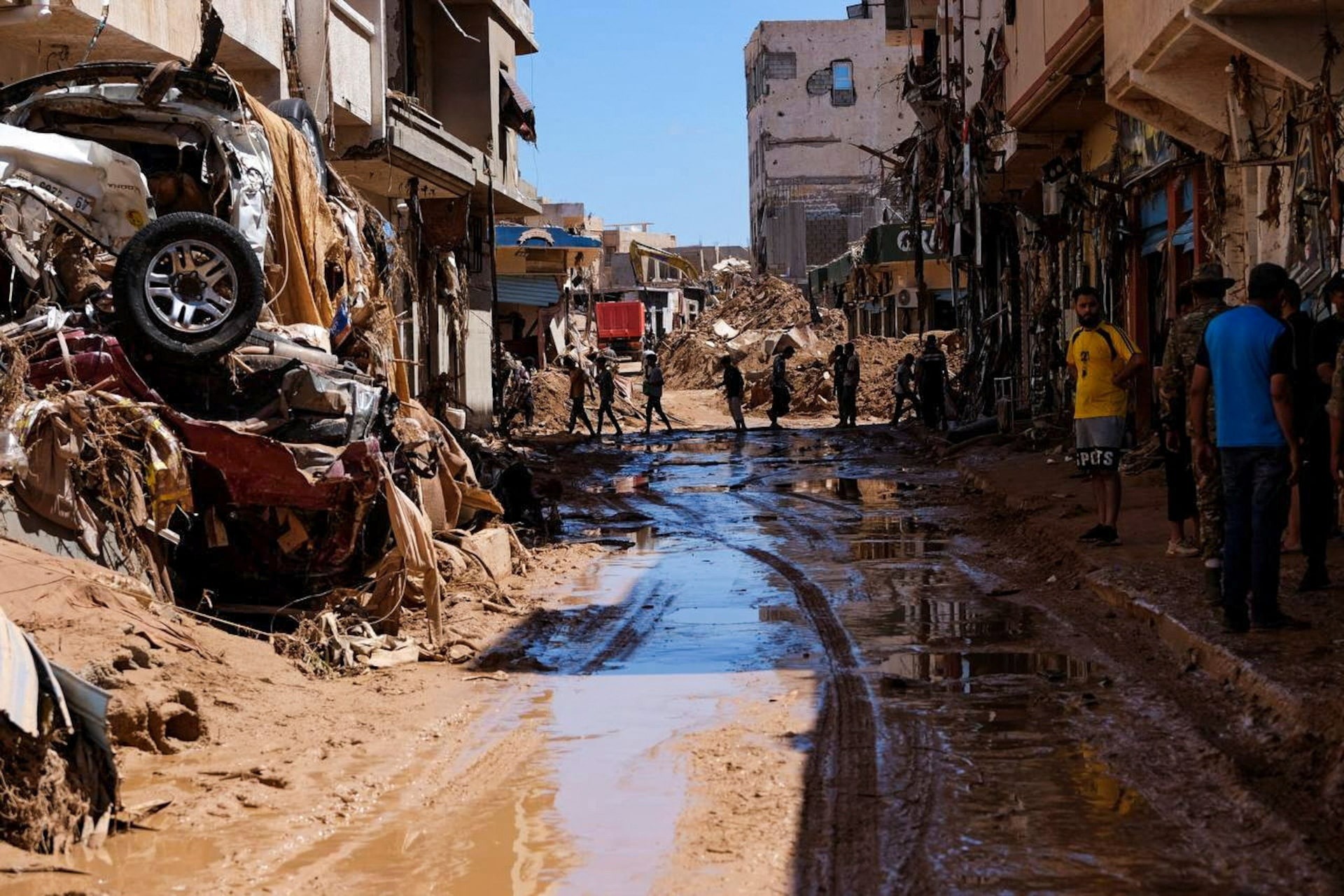 Người dân đi qua các ngôi nhà và đường phố đầy bùn đất sau thảm họa vỡ đập tại Derna, Libya ngày 13/9/2023. Ảnh: Reuters