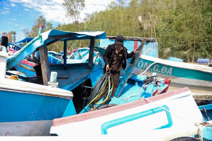Bà Hợp, 43 tuổi bên chiếc ghe cá trị giá 200 triệu đồng bị sóng đánh dạt vào bờ. "Thân ghe giờ hư hết, tôi chỉ tháo cục máy ra bán lại để gỡ gạc lại tiền vốn", bà Hợp nói.