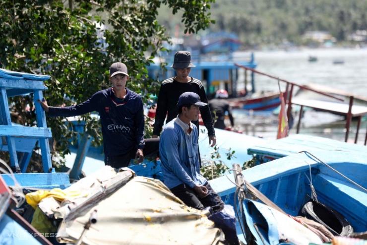 Chủ tàu thất thần bên xác ghe dạt bờ. Ngồi cạnh chiếc ghe chìm nửa thân, ông Hưng cho biết đã thuê người trục vớt từ sáng nhưng bất thành vì mắc vào nhiều tàu khác, nước lại xuống thấp. “Phải chờ thủy triều dâng mới kéo ra được, gỡ dàn máy bán lại chứ thân tàu hư hết”, ông nói.