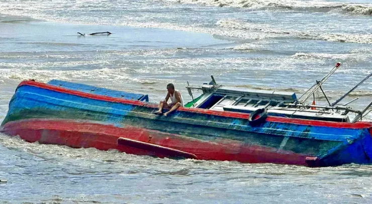 Người đàn ông ngồi câm lặng trên mạn tàu giữa cửa biển.