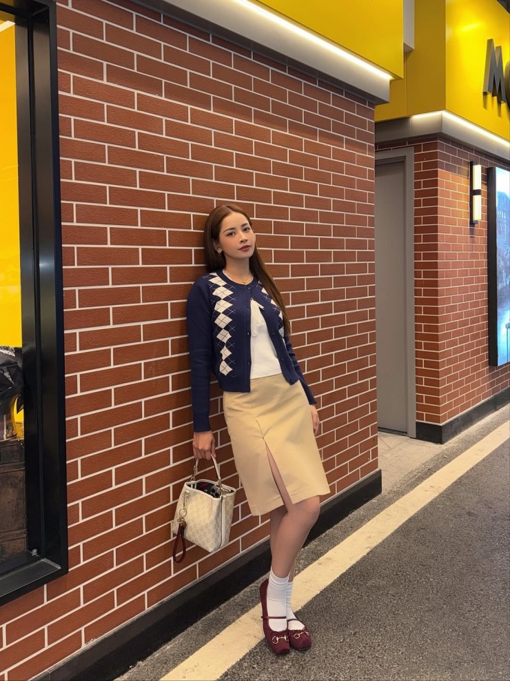 Trong chuyến du lịch Thẩm Quyến, Trung Quốc cùng bạn thân, Chi Pu chọn áo khoác len mỏng họa tiết quả trám phối chân váy xẻ đùi, giày búp bê. Ca sĩ sử dụng túi xô, kích thước nhỏ gọn nhưng vẫn đựng được nhiều đồ. Kiểu phối này phù hợp với những cô gái chuộng phong cách nữ tính.